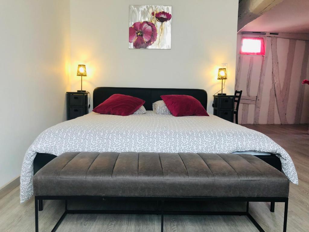 a bedroom with a large bed with red pillows at La petite Normande en ville in Louviers