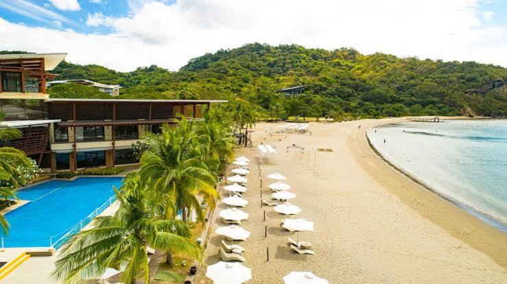 uma praia com cadeiras e guarda-sóis e um resort em Pico De Loro 2BR em Nasugbu