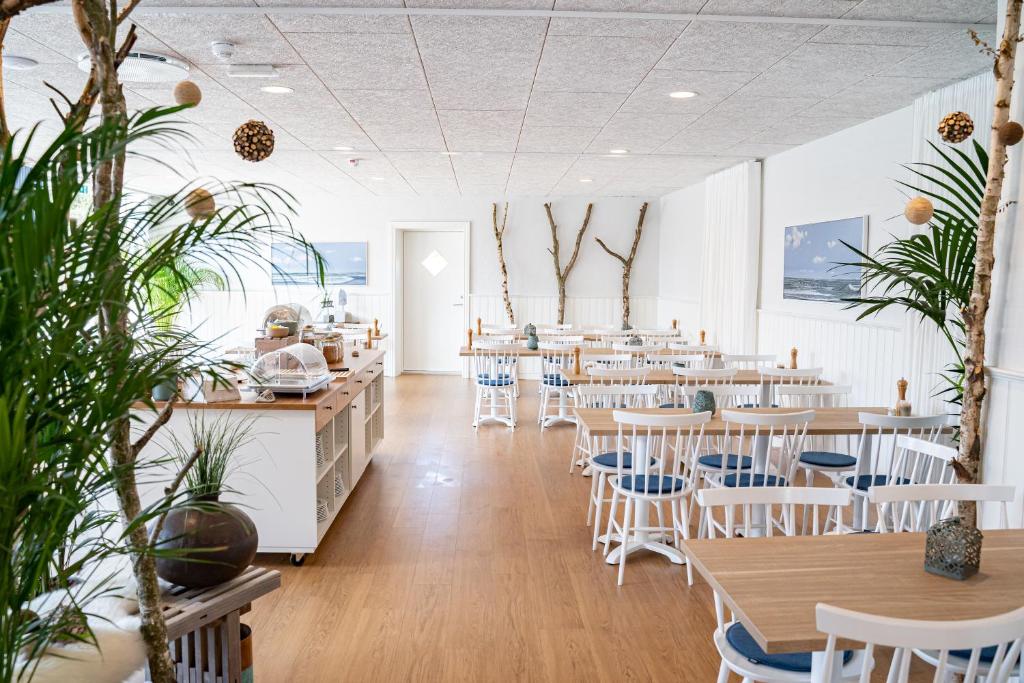 a restaurant with tables and chairs and plants at Hotel Marie in Skagen