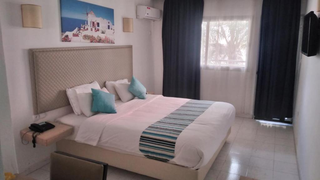 um quarto com uma cama grande e almofadas azuis em Hotel Atlal em Saidia 