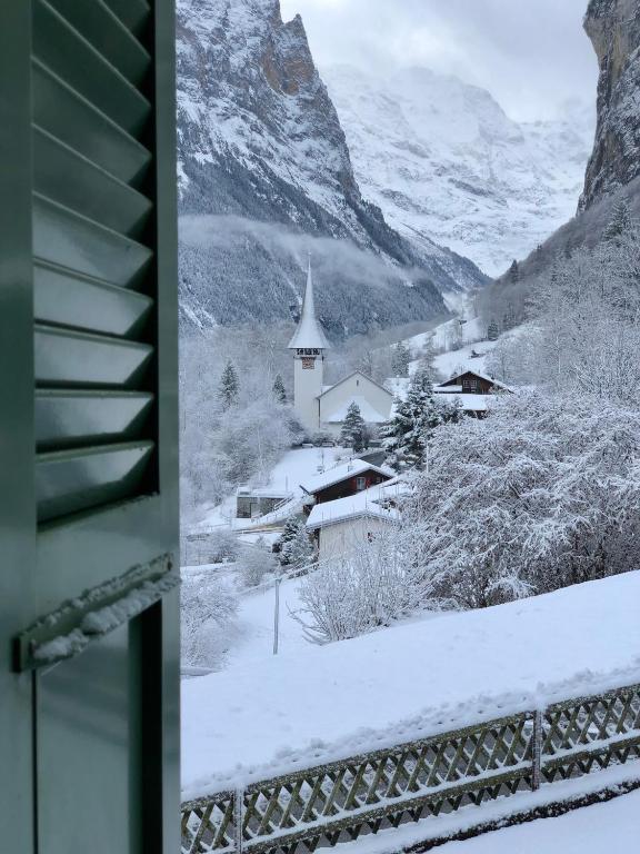 a snow covered village with a church in the mountains at Chalet Pironnet with BEST Views, Charm and Comfort! in Lauterbrunnen