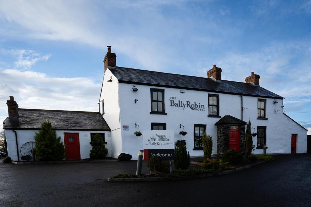 a white building with a red door on a street at Ballyrobin Hotel in Aldergrove
