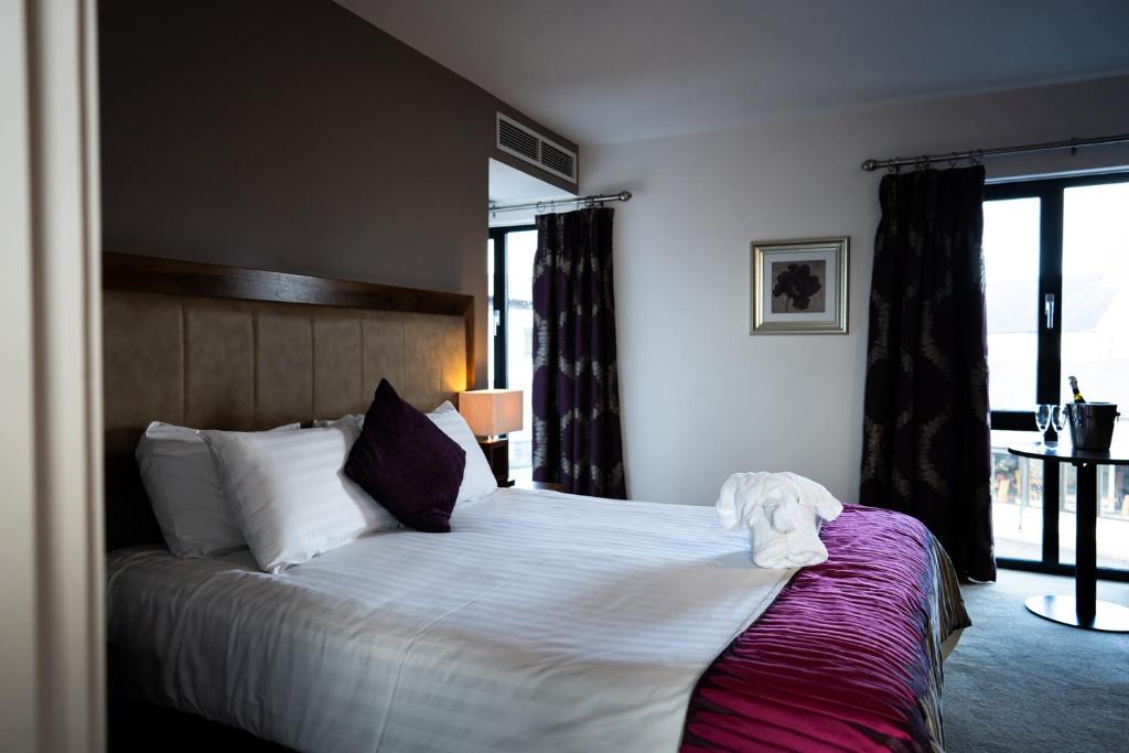 a bedroom with a large bed with white sheets and pillows at Ballyrobin Hotel in Aldergrove