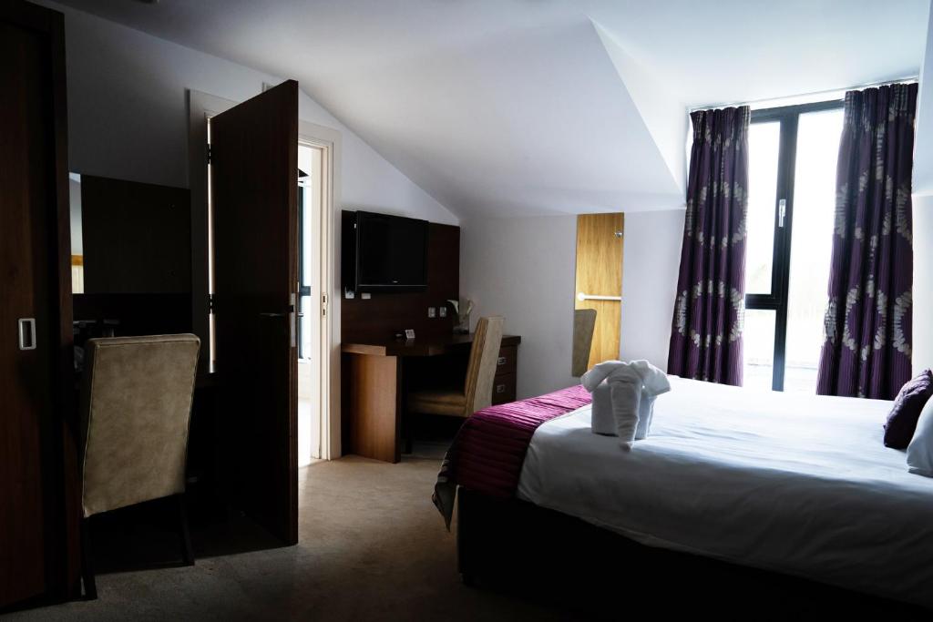 a hotel room with a bed and a desk at Ballyrobin Hotel in Aldergrove