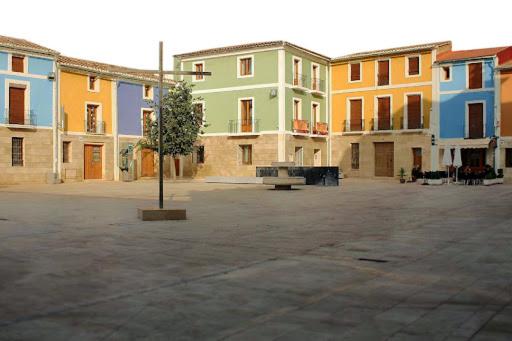 a courtyard with colorful buildings with a tree in the middle at La Casa Azul in Santa Faz