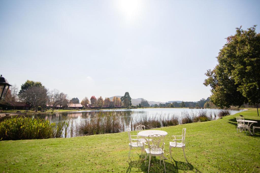 a table and chairs on the grass next to a lake at Critchley Hackle in Dullstroom