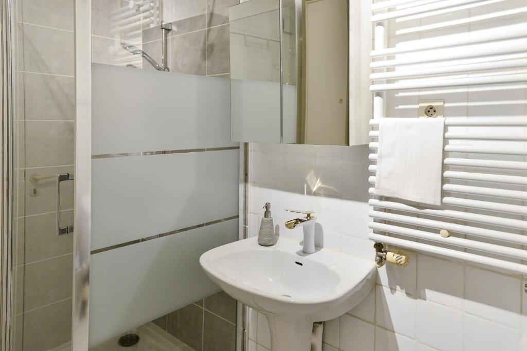 a white bathroom with a sink and a mirror at L’appartement - Jardin Secret in Marseille