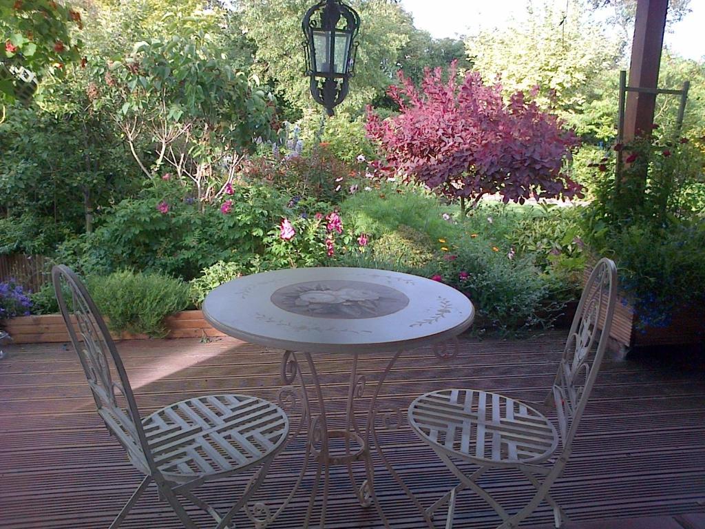 a table and two chairs on a deck with flowers at Pinetree Lodge Druridge Bay in Amble