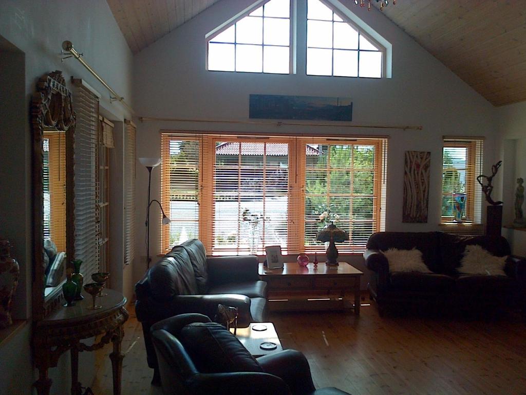 a living room with couches and a table and windows at Pinetree Lodge Druridge Bay in Amble
