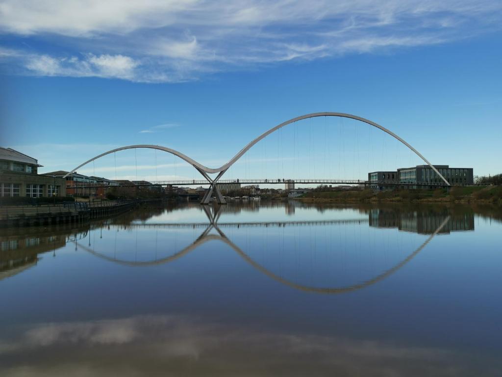 a bridge over a river with its reflection in the water at Tiger House Luxury Riverside Home in Stockton-on-Tees