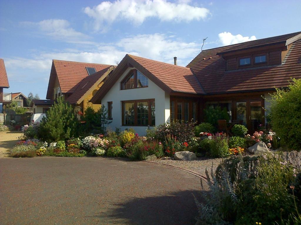 a house with a lot of flowers in the driveway at Pinetree Lodge Druridge Bay in Amble