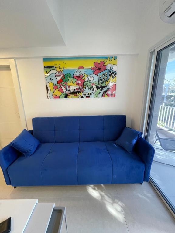 eine blaue Couch in einem Wohnzimmer mit einem Gemälde in der Unterkunft Top Royal Eilat רויאל פארק in Eilat