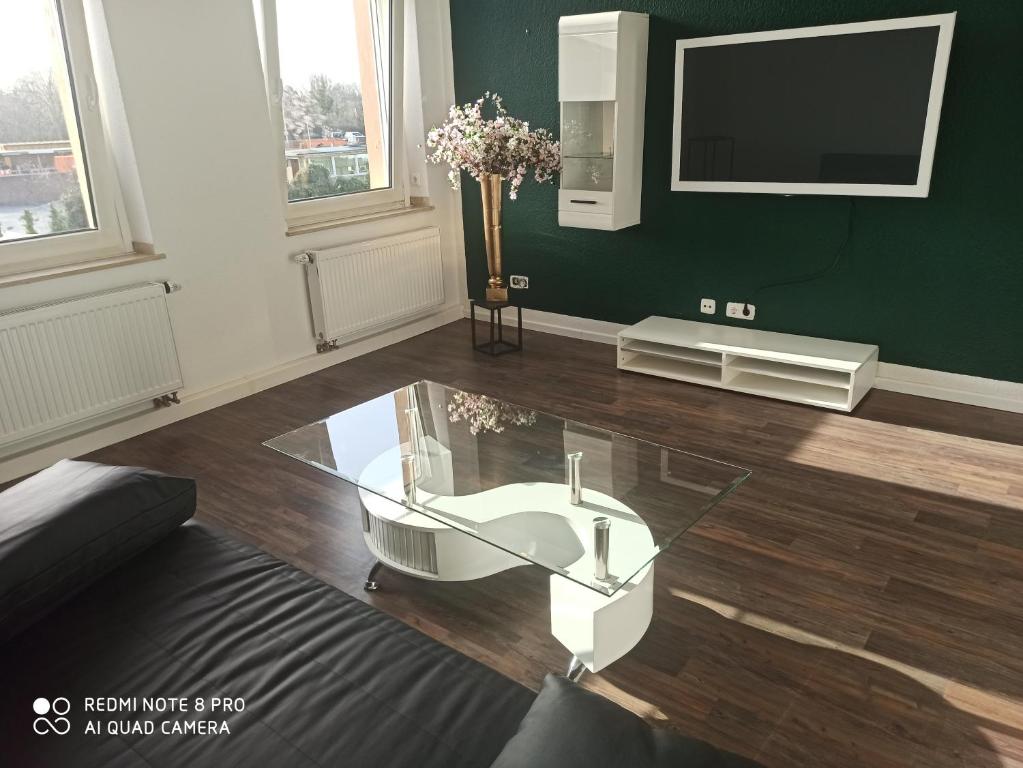 a living room with a glass table and a tv at Sky Night City Appartment in Düren - Eifel