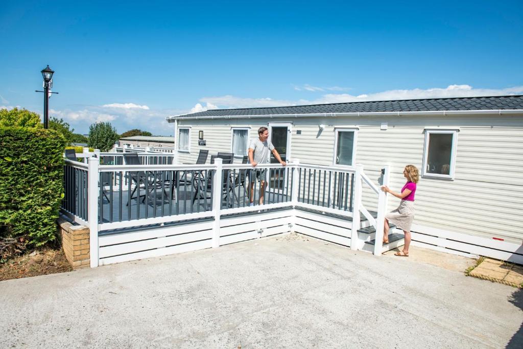 a man and a woman standing on a balcony of a house at Llanrhidian Holiday Park in Llanmorlais