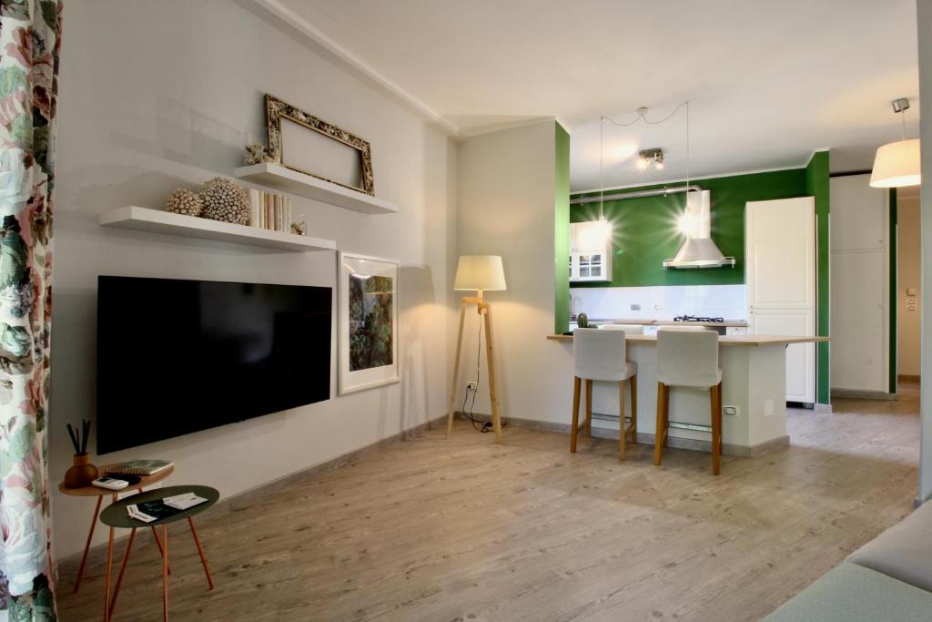 a living room with a large television and a kitchen at The Green Corner in Bordighera