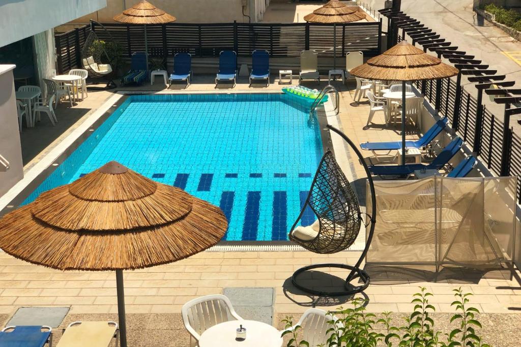 uma vista superior para uma piscina com cadeiras e guarda-sóis em Caravel Hotel Apartments em Ixia