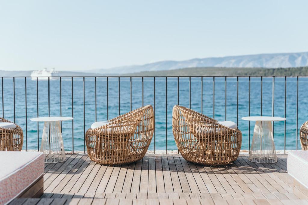 a group of chairs and tables on a deck near the water at Maslina Resort in Stari Grad