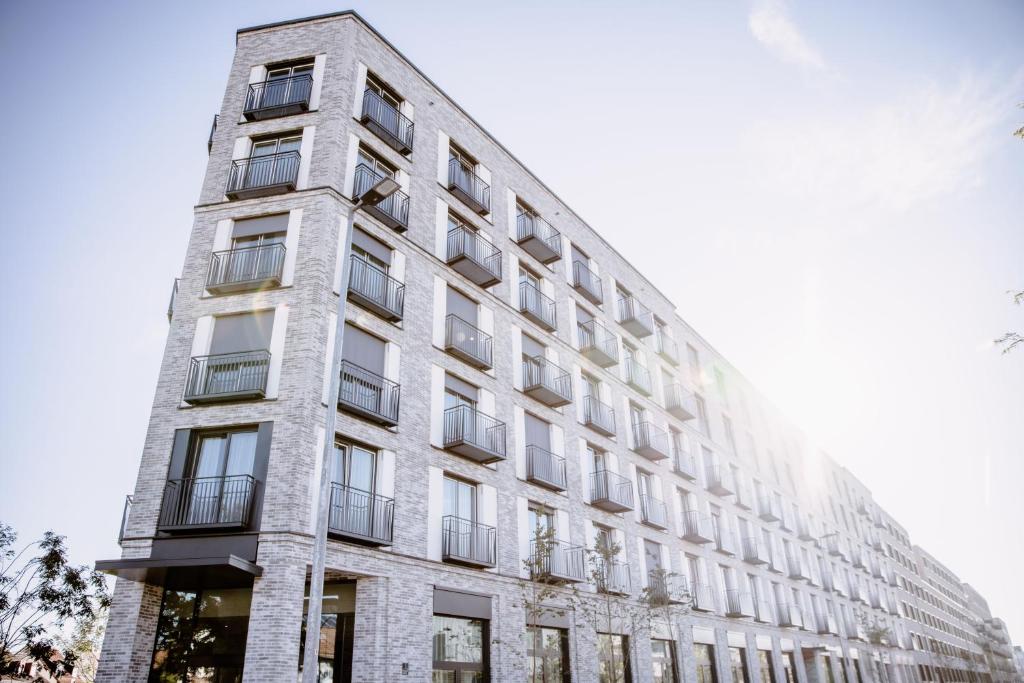 a tall white building with windows on the side of it at THE FLAG Meiller Gärten in Munich