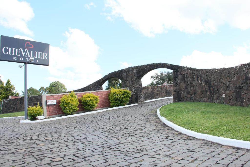 a sign for a driveway with a stone wall at Motel Chevalier in Lages