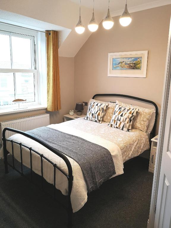 Un dormitorio con una cama con almohadas y una ventana. en Ivy Bank Guest House, Tenby, en Tenby