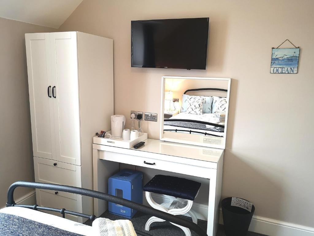 a bedroom with a dressing table with a mirror at Ivy Bank Guest House, Tenby in Tenby