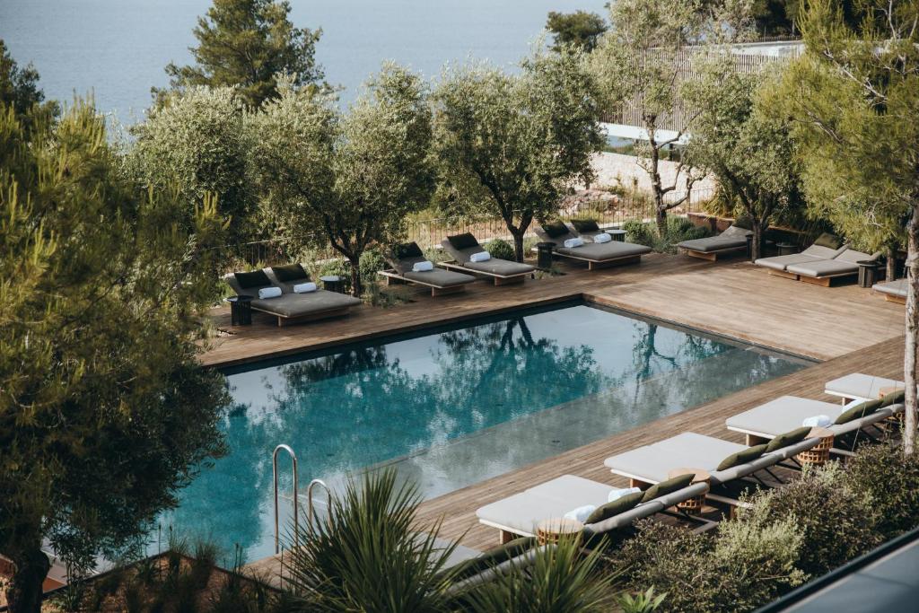 an image of a swimming pool with lounge chairs next to a swimming pool at Maslina Resort in Stari Grad
