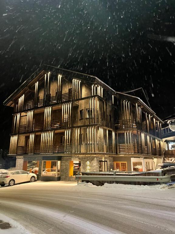 un grand bâtiment en bois avec une voiture garée devant. dans l'établissement Hotel Silvana, à Selva di Val Gardena