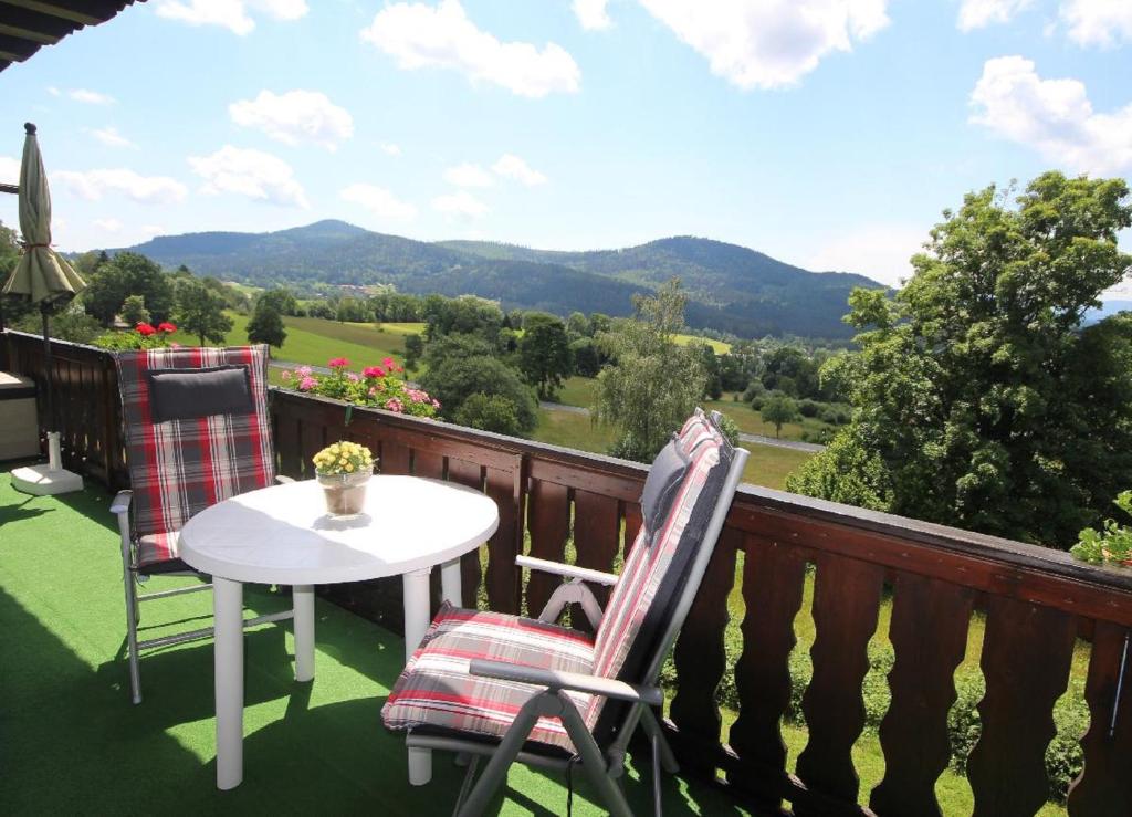 a balcony with a table and chairs and mountains at FW Zum Königshang in Bodenmais
