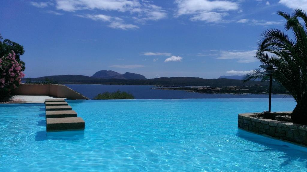a swimming pool with a view of a body of water at Ladumar Sardinia in Porto Rotondo