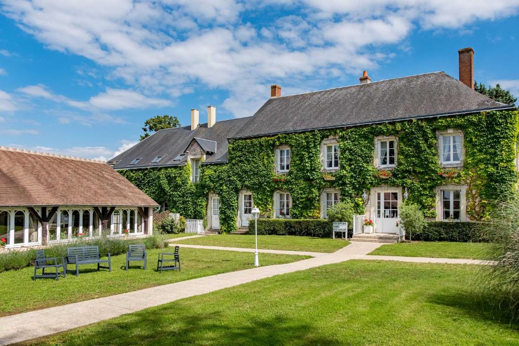 a building covered in ivy with chairs in the yard at Logis Le Fleuray in Cangey