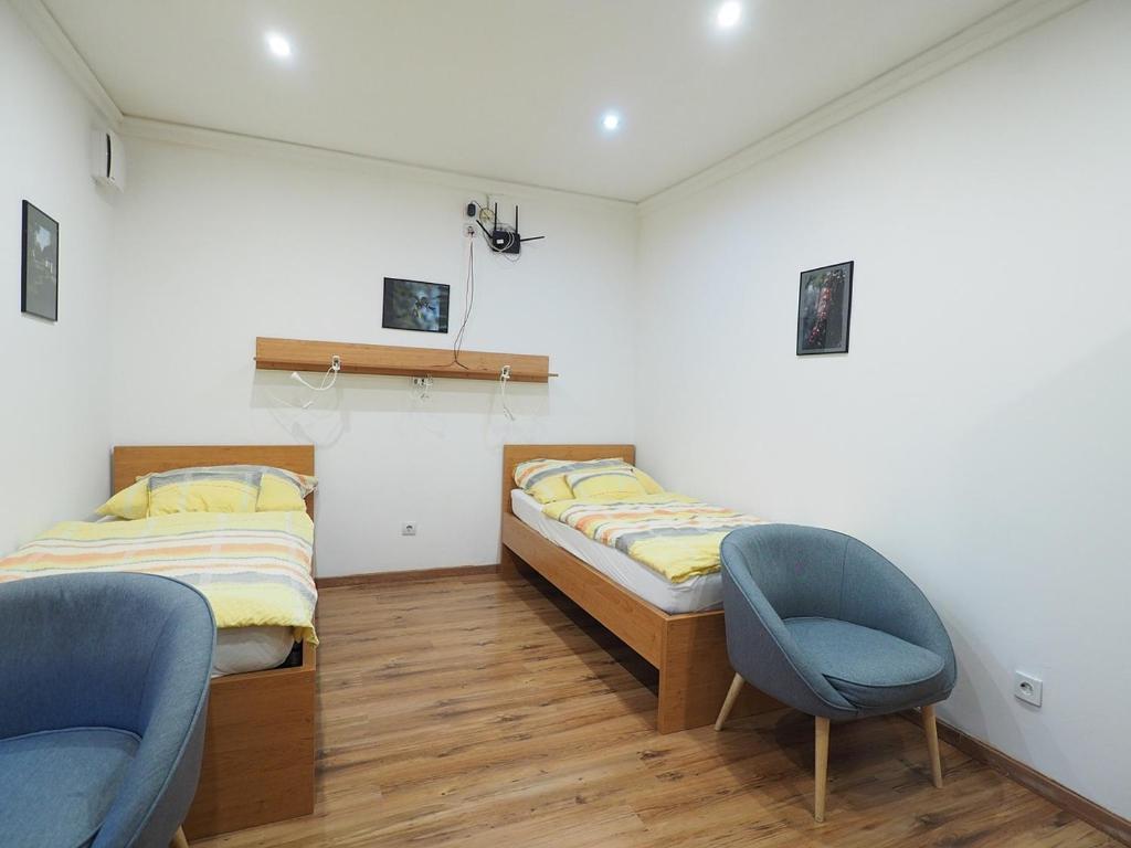 two beds in a room with two chairs at Pajger Apartman in Pécs