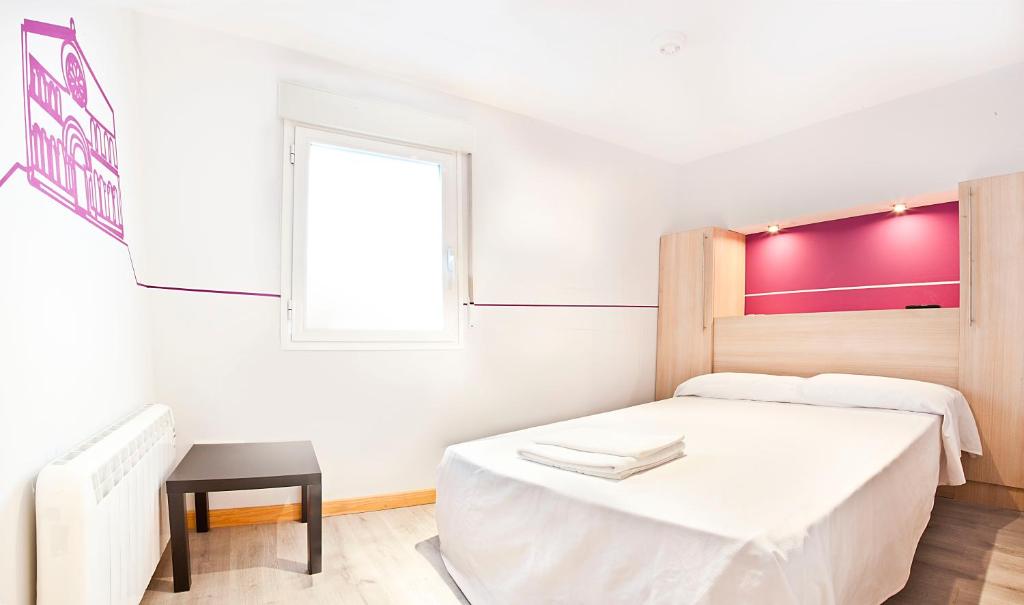 a white bedroom with a bed and a window at Pensión Herradores in Soria