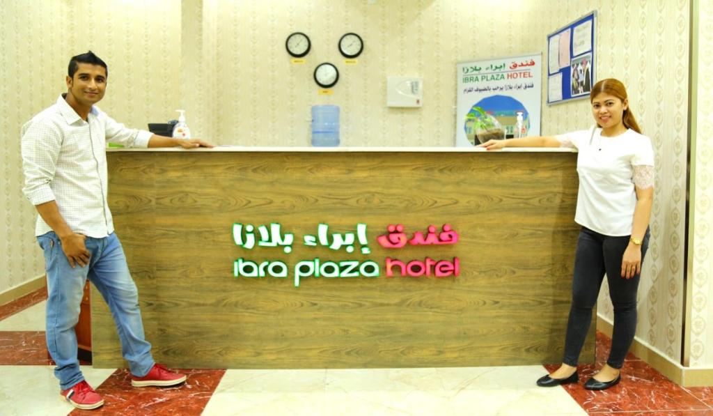 a man and a woman standing in front of a counter at Ibra Plaza Hotel in Ibrā