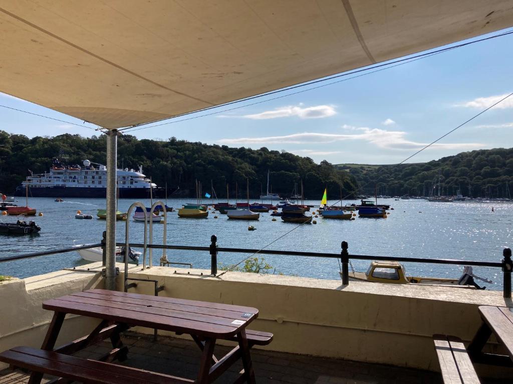 a picnic table on a balcony with boats in the water at The Galleon Inn in Fowey