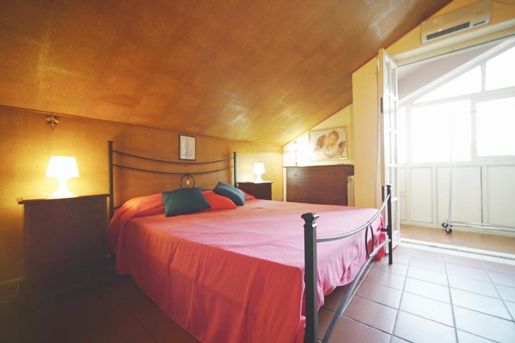 sypialnia z łóżkiem z czerwoną pościelą i oknem w obiekcie Etna Rooftop Apartment w mieście Pedara