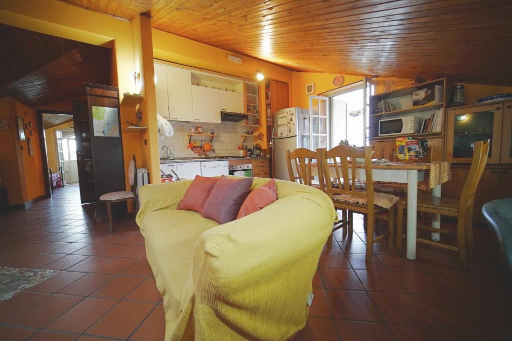 salon z żółtą kanapą i kuchnią w obiekcie Etna Rooftop Apartment w mieście Pedara