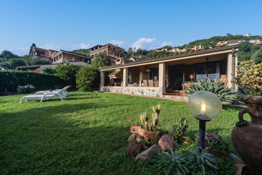 una casa con un prato verde con una candela in cortile di Villa Monica a Costa Rei