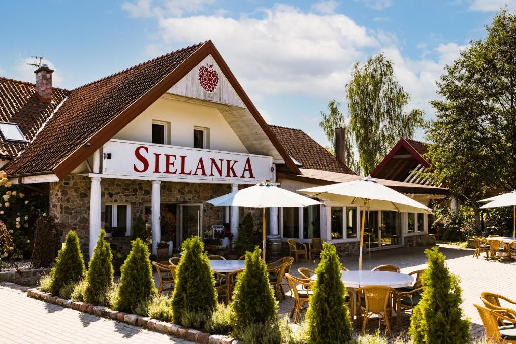 a hotel with tables and umbrellas in a courtyard at Kozi Dwór - Sielanka in Gietrzwałd