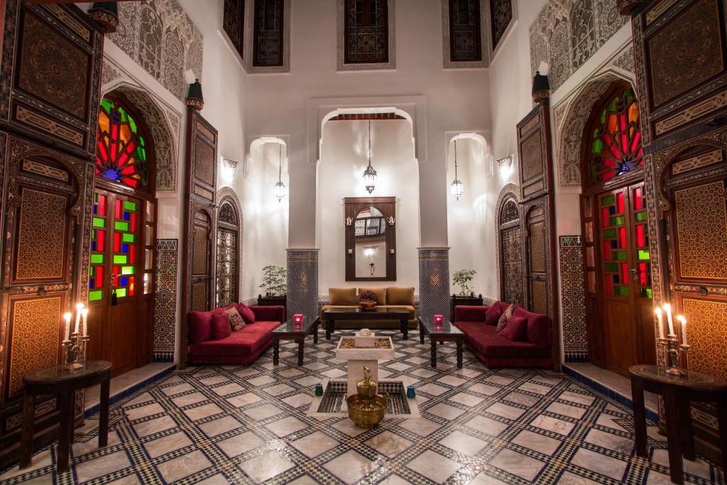 a lobby with red chairs and stained glass windows at Riad Noujoum Medina in Fez