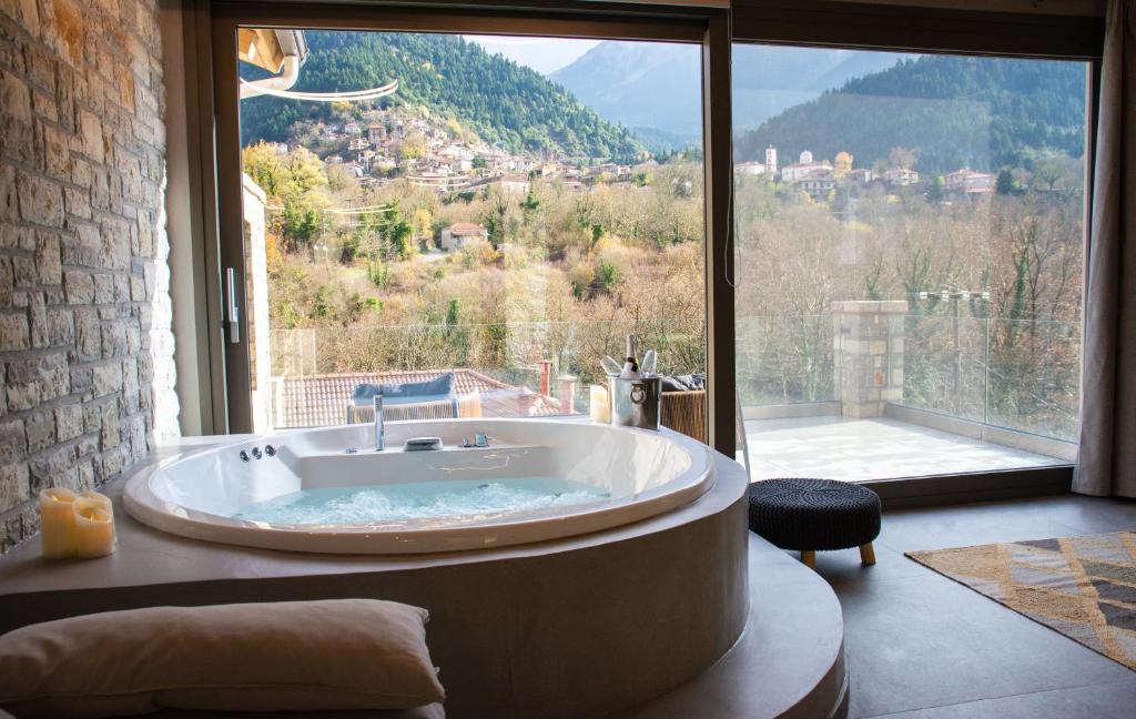 eine große Badewanne in einem Zimmer mit einem großen Fenster in der Unterkunft Evora Luxury Suites in Méga Khoríon