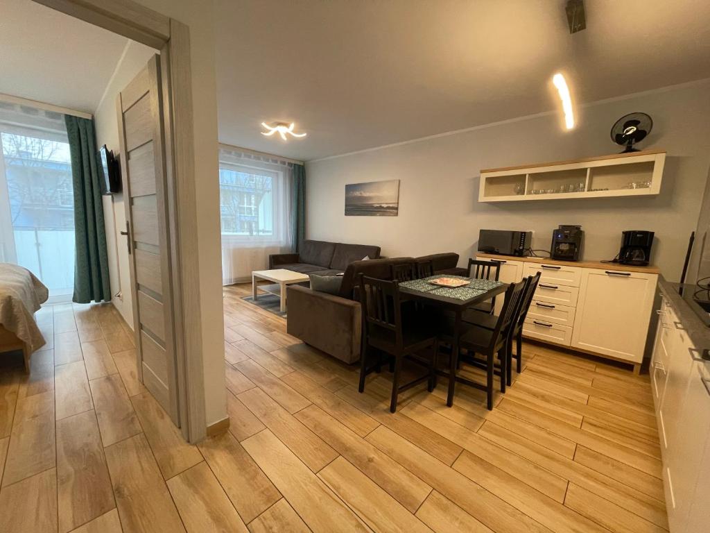 a kitchen and living room with a table and a couch at Closer to the Sea Apartments in Kołobrzeg