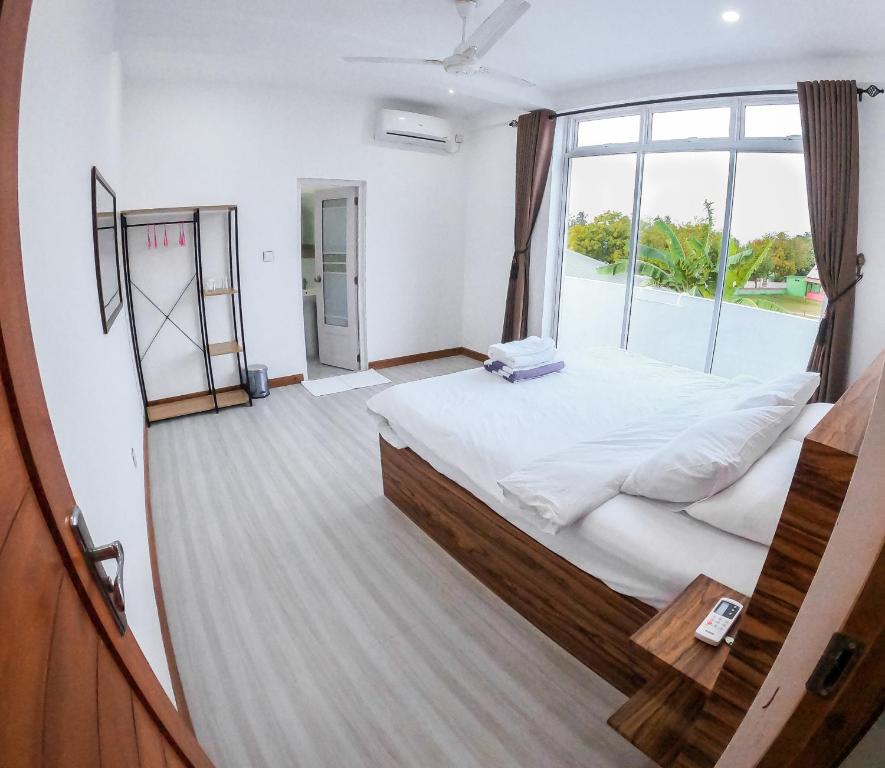 1 dormitorio con cama grande y ventana grande en Akiri Surf Residence, en Thulusdhoo