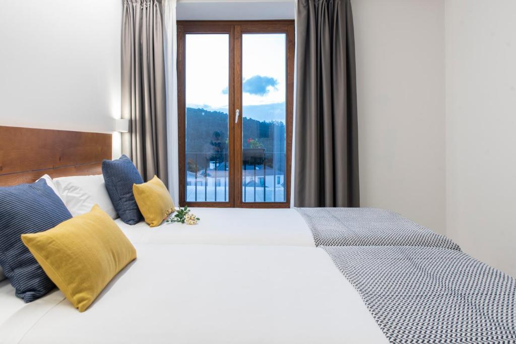 Cama blanca con almohadas azules y amarillas y ventana en LIRESCA, en Lires