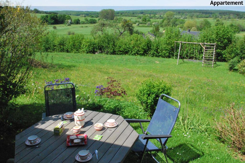 une table en bois et deux chaises dans un champ dans l'établissement La petite source, à Florenville