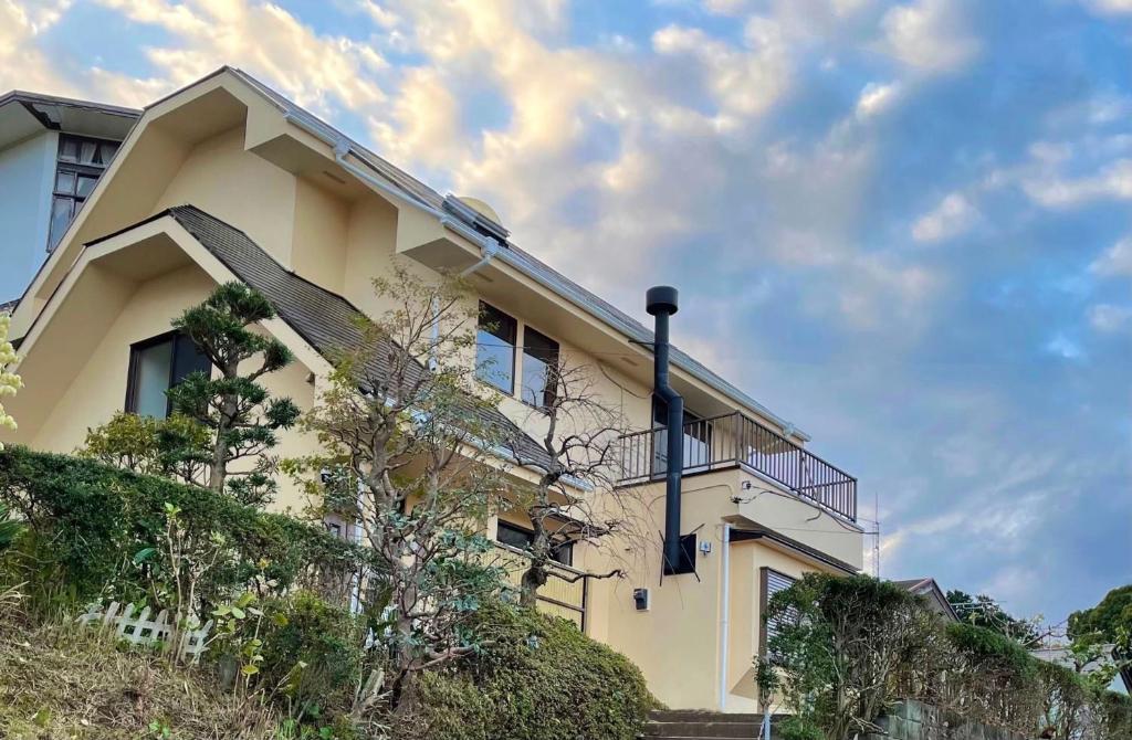 una casa gialla con balcone su una collina di Miyabi-Minami Atami - Vacation STAY 98795v ad Atami