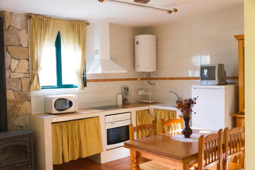 a kitchen with a table and a white refrigerator at Apartamentos Rurales Mayorazgo in Cañete