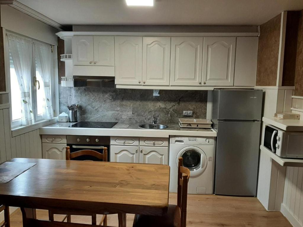 a kitchen with white cabinets and a table and a sink at BARRIO DE ABAJO Nº 50 in Felechosa