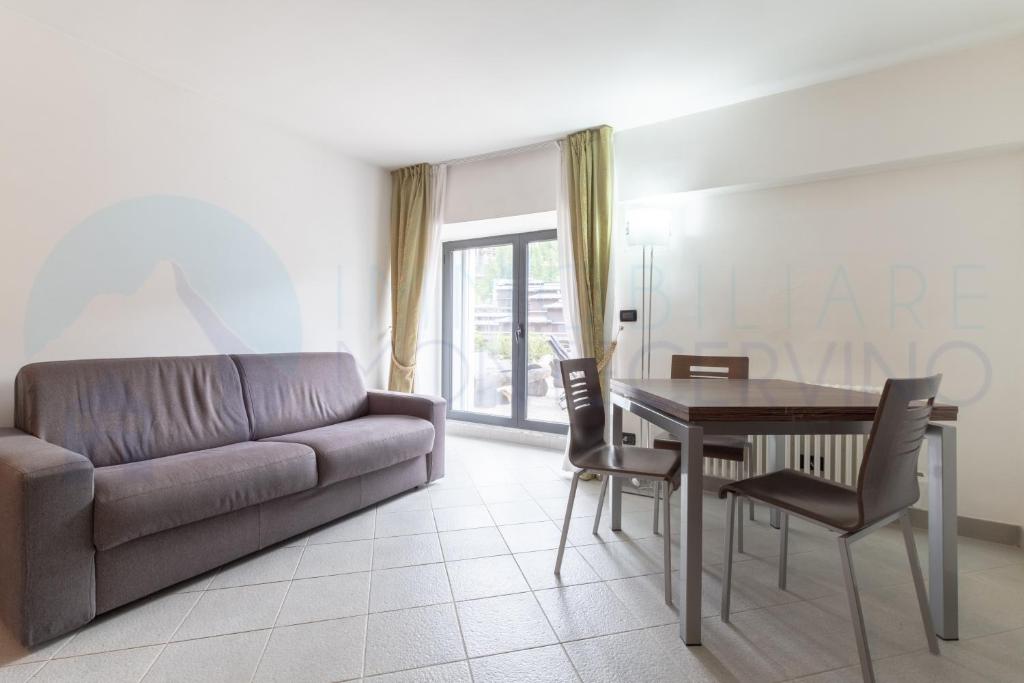 a living room with a couch and a table and chairs at Bilocale in centro con terrazzo e wifi - AS11 in Breuil-Cervinia
