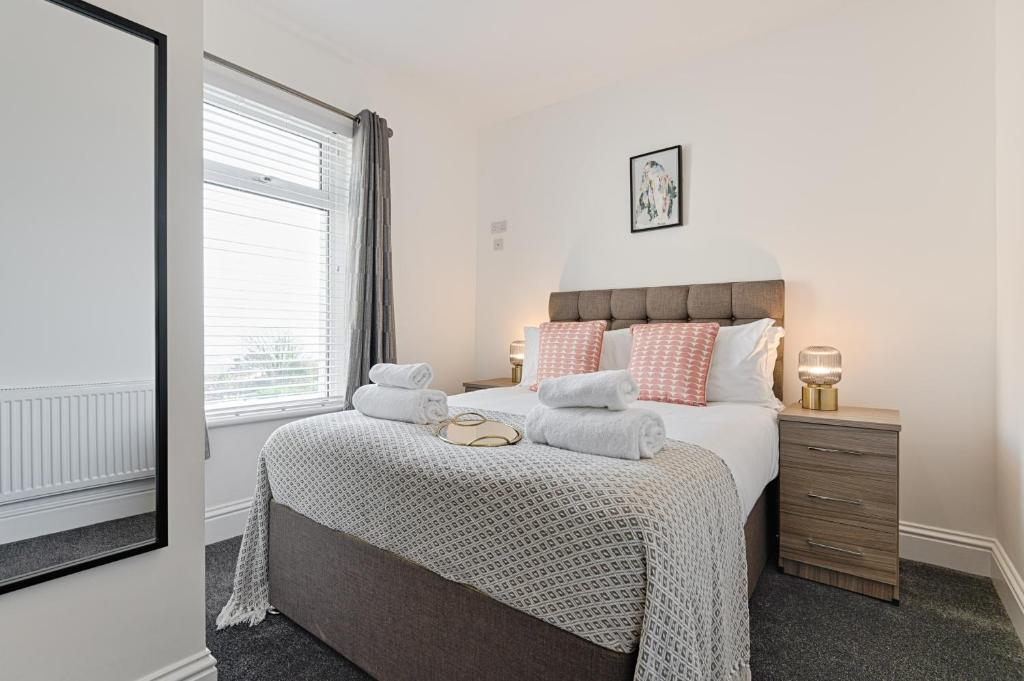 een slaapkamer met een bed met kussens en een raam bij Caemawr Place - Stylish Home TV in Every Bedroom! in Swansea