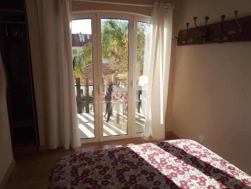 Un dormitorio con una cama y una puerta corrediza de vidrio. en Nora Velha T1, en Tavira